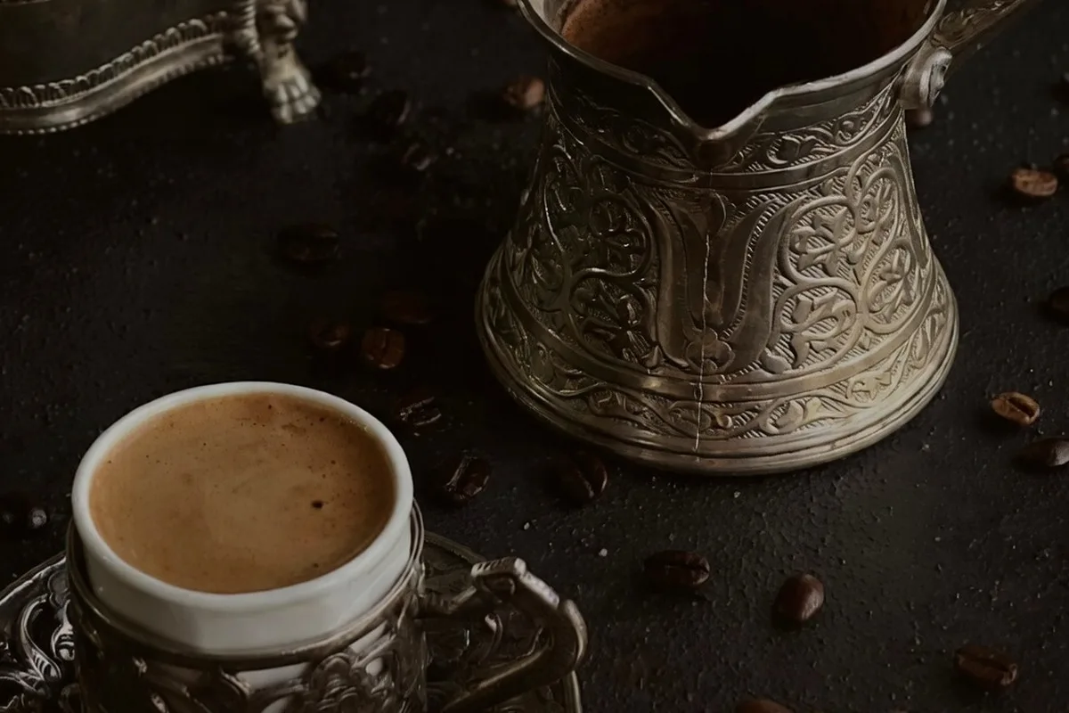 Turkish coffee poured from a cezve into a patterned cup