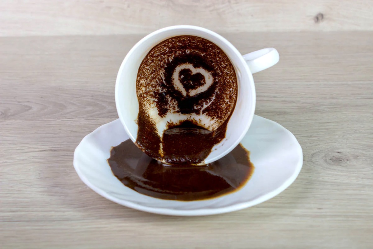 Close-up of coffee grounds in a white cup showing heart-shaped patterns