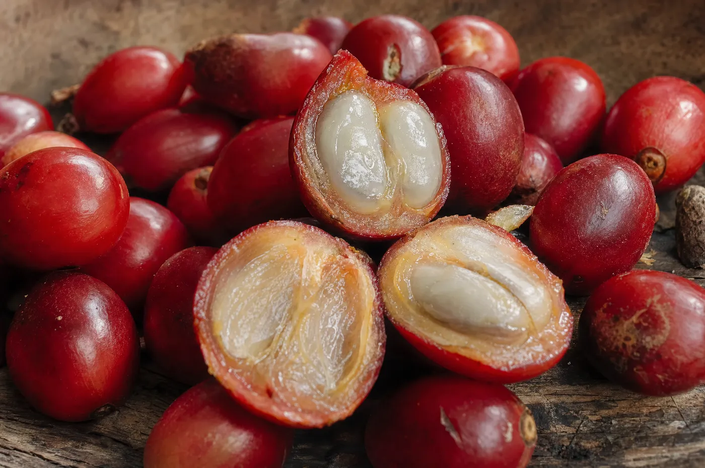 Ripe coffee cherries split open to show the fruit and the two seeds inside