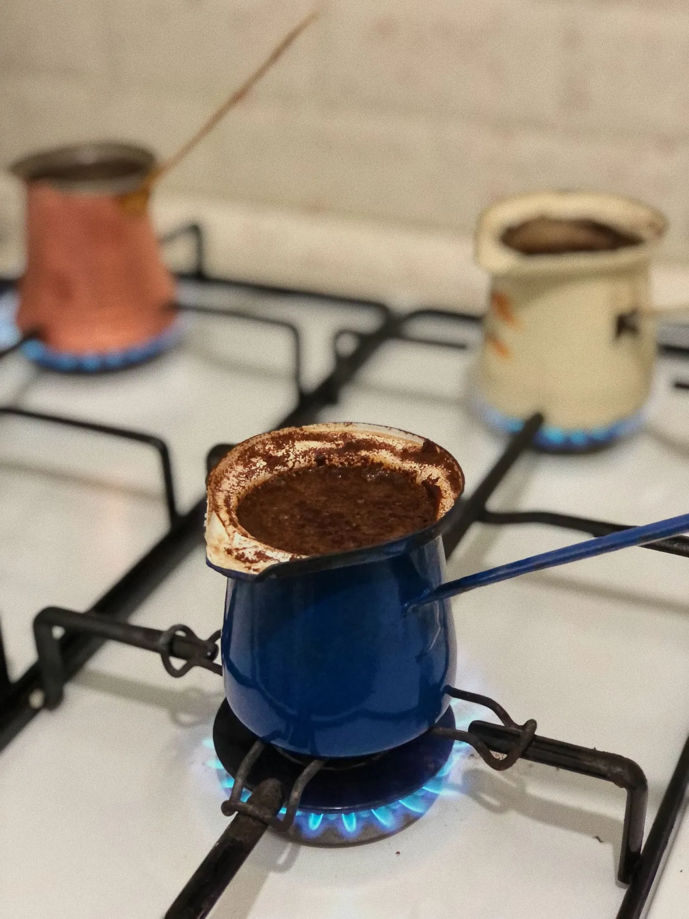 A copper cezve heating on a gas stove