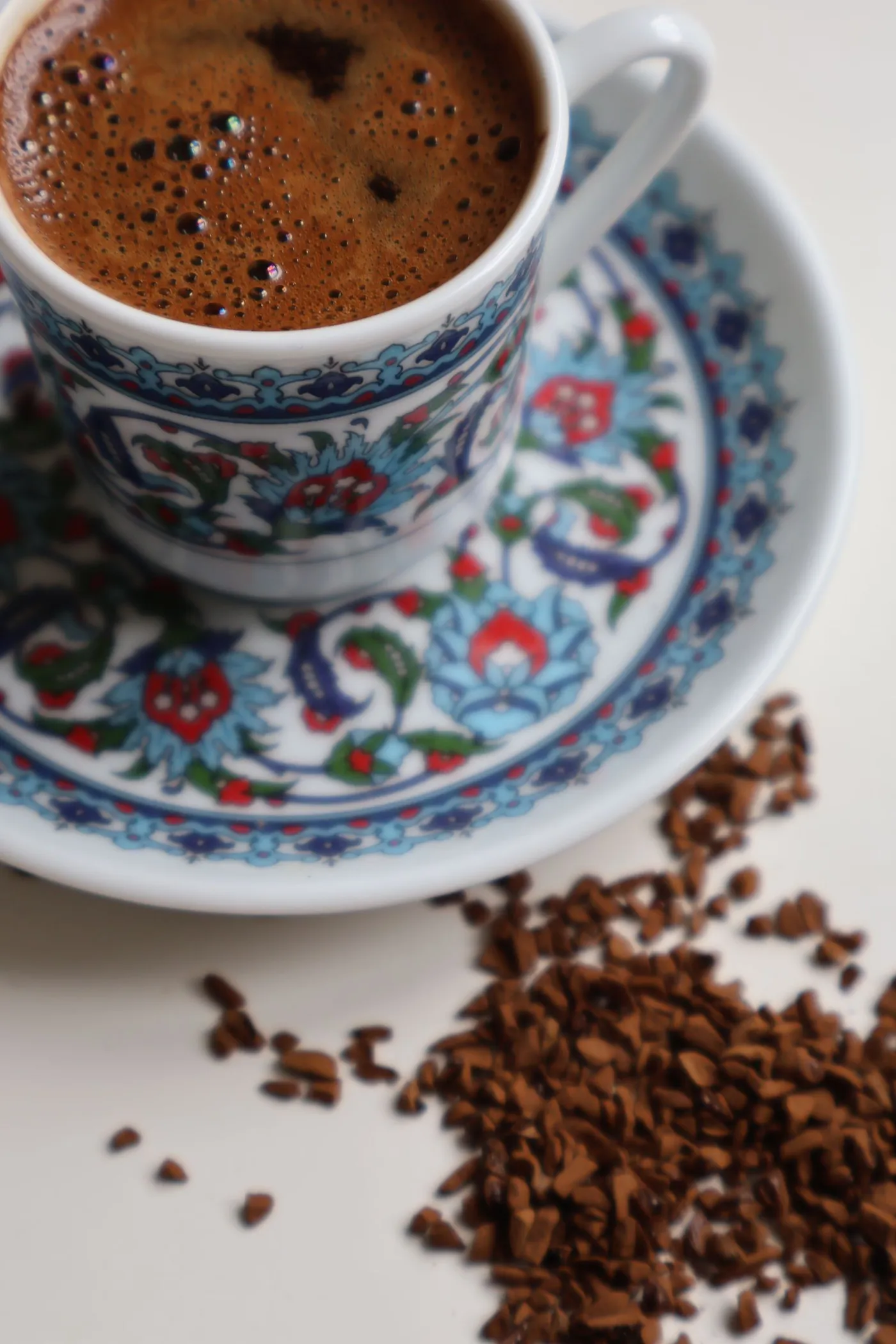 A cup of Turkish coffee with ground coffee scattered beside it